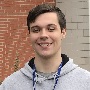 This image depicts a photograph of Preston standing in front of the library.